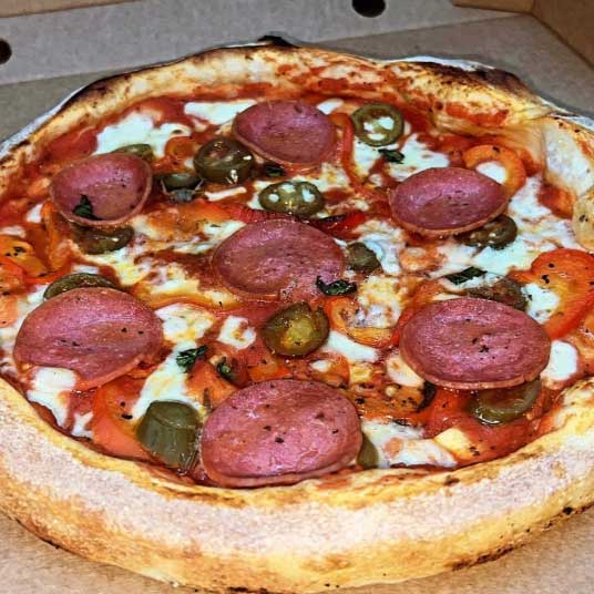 A close-up of a pizza from Vinnie's with pepperoni, jalapenos and bell peppers.